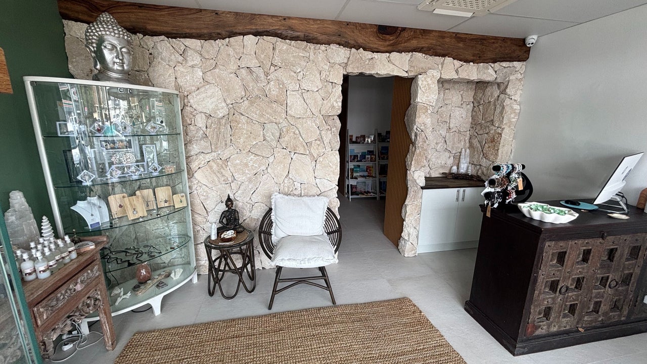 Inside The Healing Cottage Palm Beach with natural stone wall, Buddha, and retail cabinet